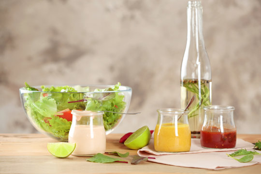 Jars with tasty sauces for salad on table