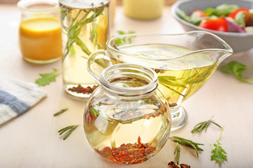 Jar and gravy boat with tasty salad dressings on table