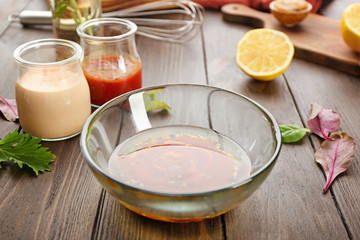 Bowl with tasty sauce for salad on table