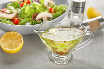 Gravy boat with tasty salad dressing on table