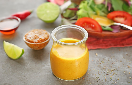 Jar with tasty sauce for salad on table