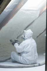 spray polyurethane foam for roof - technician spraying foam insulation using plural component gun for polyurethane foam, inside