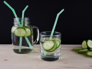 Glasses of cucumber detox water. Homemade cold gin tonic with basil on wooden table