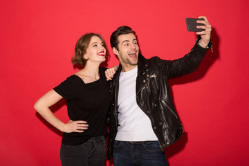 Happy punk couple posing and making selfie on smartphone