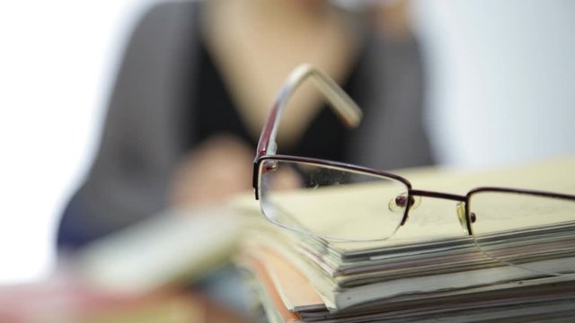 glasses on a pile of exercise books, woman works without glasses after vision correction