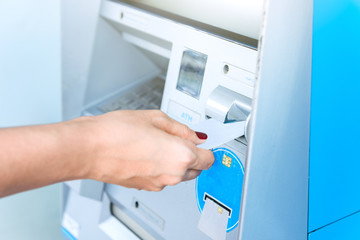Hand inserting ATM card into bank machine for withdraw money