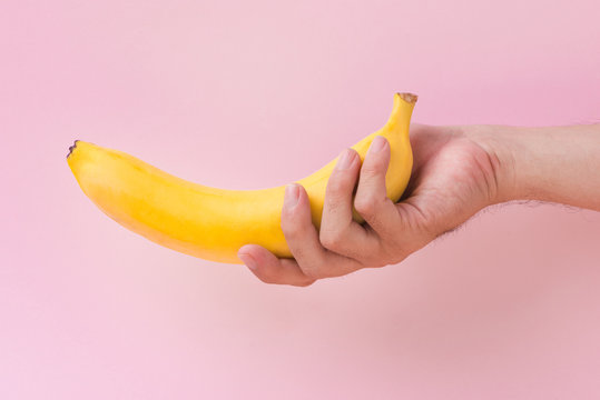 a man holding a banana isolated on pink background