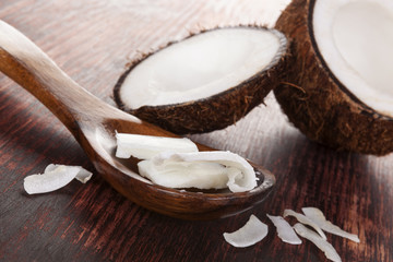 Coconut oil in spoon on wooden table.