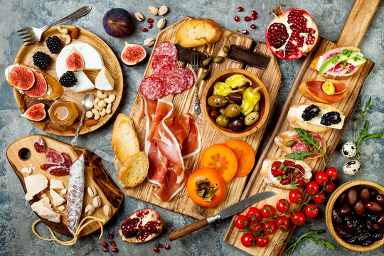 Fototapeta Appetizers table with italian antipasti snacks. Brushetta or authentic traditional spanish tapas set, cheese variety board over grey concrete background. Top view, flat lay