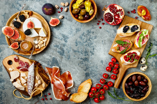 Appetizers table with italian antipasti snacks. Brushetta or authentic traditional spanish tapas set, cheese variety board over grey concrete background. Top view, flat lay, copy space