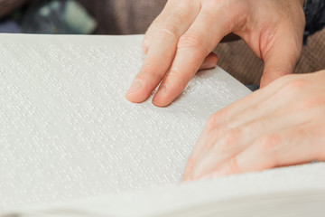 The blind man was reading a book written on Braille. Touch your finger on the braille code. A book...