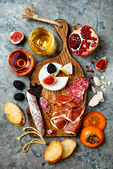 Appetizers table with italian antipasti snacks and wine in glasses. Charcuterie and cheese board over grey concrete background. Top view, flat lay