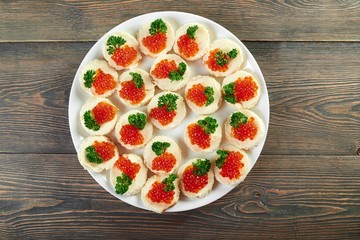 Top view horizontal shot of a plate with buttered canapes with red caviar decorated with greens copyspace luxury expensive dish food eating healthy delicious appetizer restaurant.