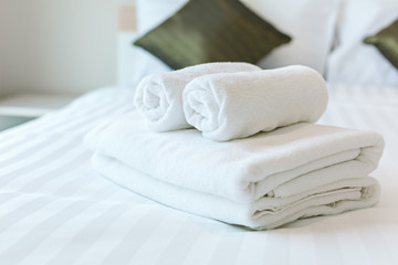 Fototapeta na wymiar Freshly laundered fluffy towels on bed in hotel