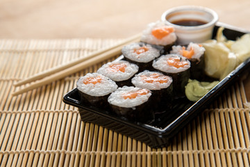 Lachs Maki Sushi vom Lieferdienst mit Ingwer, Wasabi, Sojasoße und Holz Stäbchen