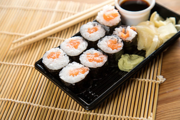 Lachs Maki Sushi vom Lieferdienst mit Ingwer, Wasabi, Sojasoße und Holz Stäbchen