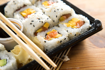 Lachs Mango Frischkäse Inside Out Sushi in Lieferdienst Verpackung mit Stäbchen