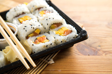 Lachs Mango Frischkäse Inside Out Sushi in Lieferdienst Verpackung mit Stäbchen