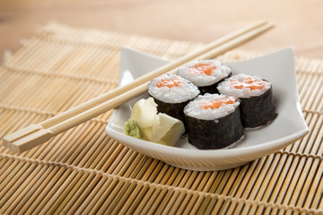 Vier Maki Sushi mit Lachs auf Teller an Holz Stäbchen