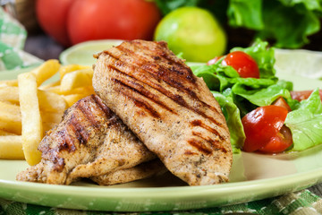 Grilled chicken breasts served with fries