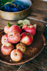 Fresh red apples in a rusty tray, grapes in a steel bowl, on an old wooden background.