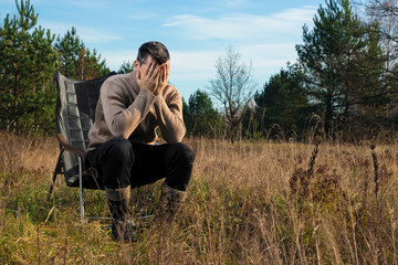 A man is sitting in a rocking chair in nature. The concept of outdoor recreation.