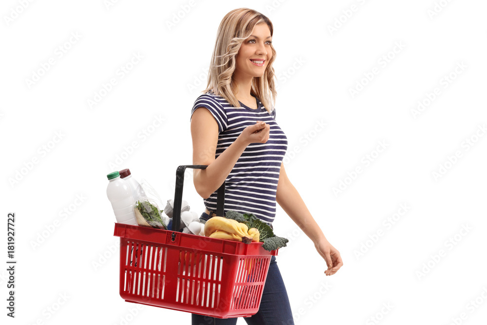 Wall mural young woman holding a shopping basket filled with groceries