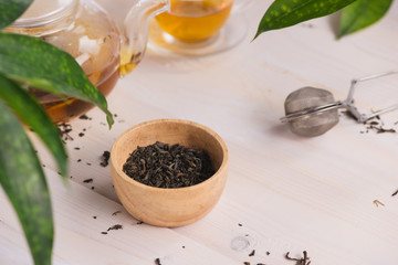 Dry tea in bowl, on wooden background
