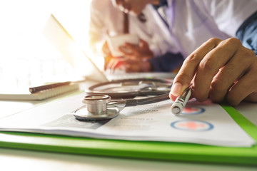 Medicine doctor hand working with modern computer and smart phone,digital tablet with his team on white desk as medical concept in morning light
