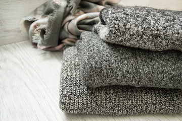 Three gray sweaters on a wooden background. Fashionable concept.