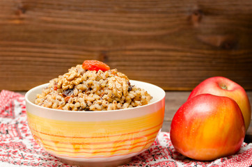Apples and dish of traditional Slavic treat on Christmas Eve  on a patterned tablecloth. Brown wooden background. Copy space.