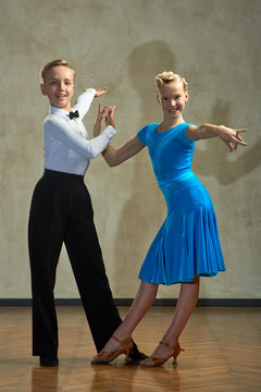 Attractive young couple of children dancing ballroom dance in studio