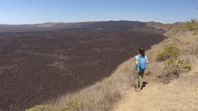 Galapagos tourist hiking on volcano Sierra Negra on Isabela Island. Woman on hike visiting famous landmark and tourist destination, wolds 2nd largest active volcanic caldera, Galapagos Islands Ecuador