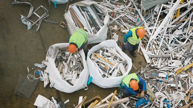 Top view of workers packing metal garbage in big bags