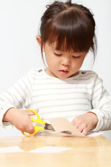 Naklejka premium はさみで紙を切る幼児(3歳児)