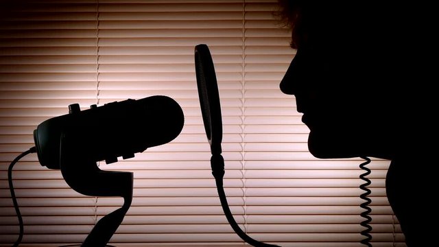 A man putting on headphones then speaking into a microphone to make an audio broadcast.