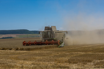 Fototapeta premium Close-up of a working harvester's back at harvest time. A dust and straw fertilizer. Concept farming and agriculture.