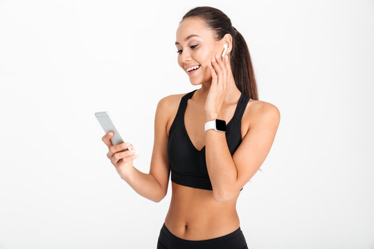Portrait of a smiling asian fitness woman listening to music