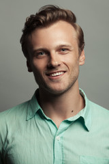 Obraz premium Male beauty, boy next door concept. Portrait of smiling 30-year-old man standing over gray background. Close up. Classic style. Wavy glossy blond hair. Studio shot