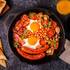 Traditional full English breakfast with fried eggs, sausages, beans, mushrooms, grilled tomatoes and bacon.