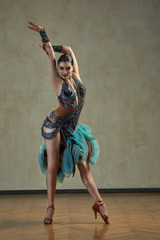 Attractive woman dancing ballroom dance in studio in gorgeous sexy latin costume
