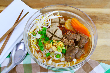 Thai style chicken noodle soup in glass bowl.