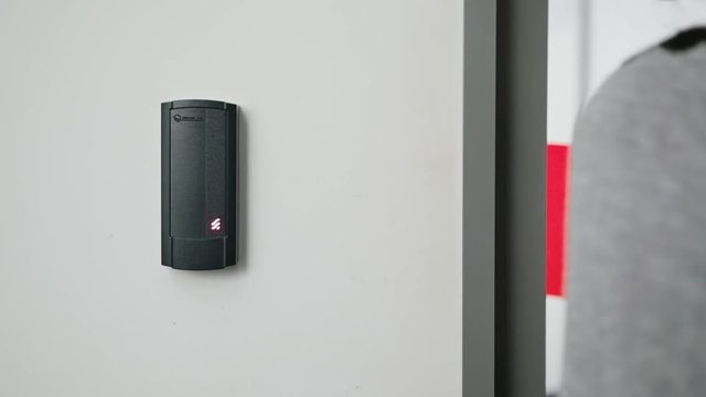 Close up of a woman using a modern intercom at a residential building entrance.