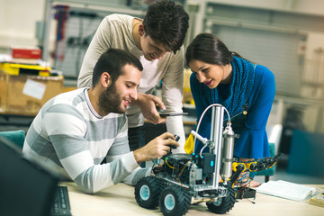 Young students of robotics preparing robot for testing in workshop