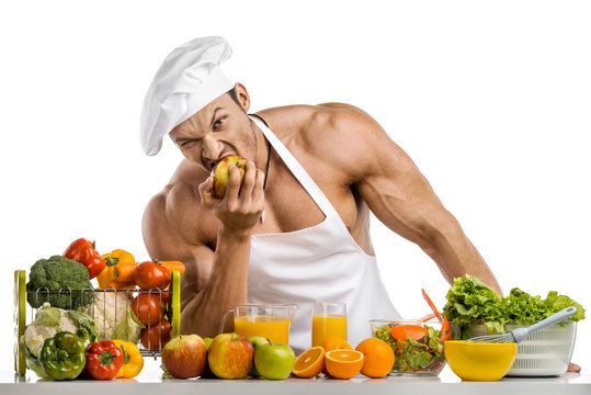 Man bodybuilder in white toque blanche and cook protective apron eat apple