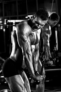 very power athletic guy bodybuilder,  execute exercise with gym apparatus, on triceps
