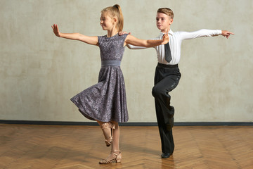 Attractive young couple of children dancing ballroom dance in studio - obrazy, fototapety, plakaty