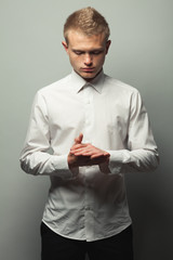 Fashionista concept. Portrait of brutal young man with short blond hair and freckles on face wearing white shirt and posing over gray background. Hipster style. Studio shot