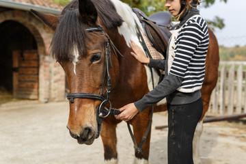 Ready for riding! -The girl holds her horse for reins