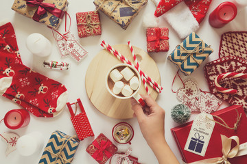 Christmas background with handmade presents wrapped in craft paper, cup of hot chocolate. Flat lay. Space for copy